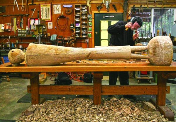 David Hostetler carving a reclining female wood sculpture in his studio